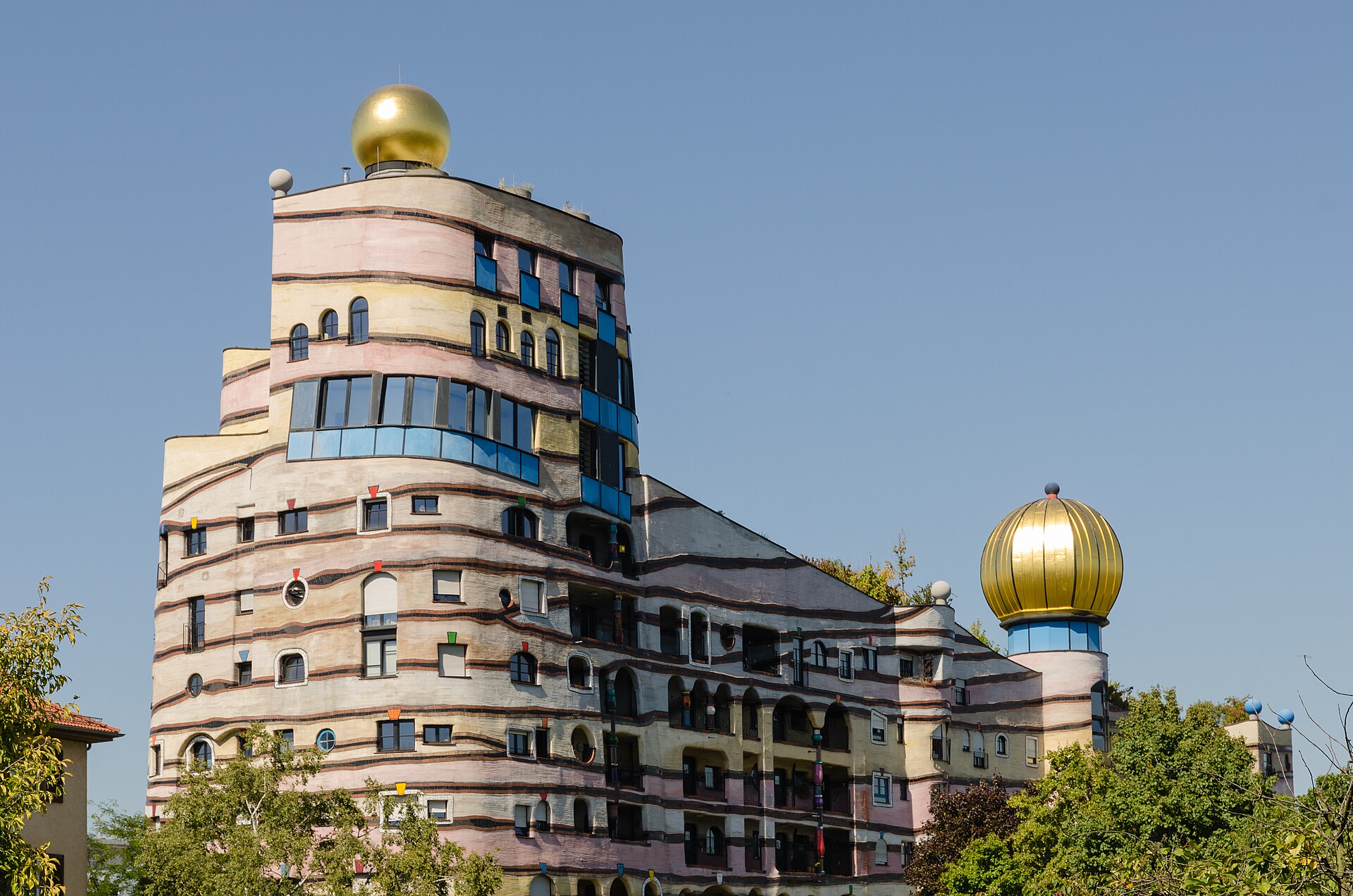 The Waldspirale in Darmstadt: a curving residential block with mature trees growing from its planted roof.